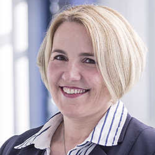 Porträt einer Frau mit blonden, schulterlangen Haaren und einem gestreiften Hemd, lächelnd in die Kamera.