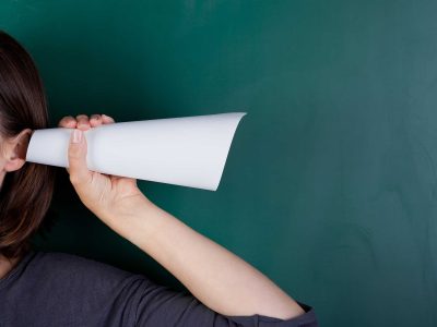 Eine Person hält eine Papiertüte an ihr Ohr, um besser zuzuhören.