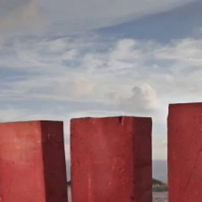 Ein Mann im Anzug steht auf einer roten Säule und schaut mit einem Fernglas in die Ferne.