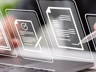 Person, die mit einem digitalen Stift auf einem Laptop Dokumente bearbeitet und überprüft.